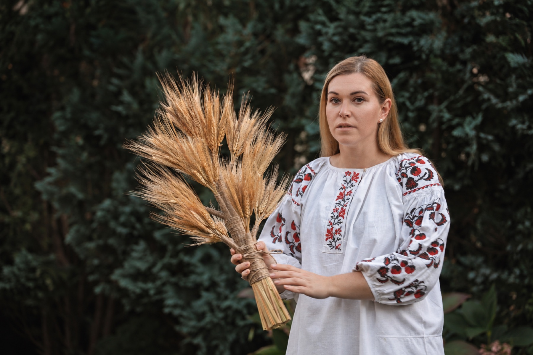 Lubomira w haftowanej koszuli trzyma związany snop pszenicy
